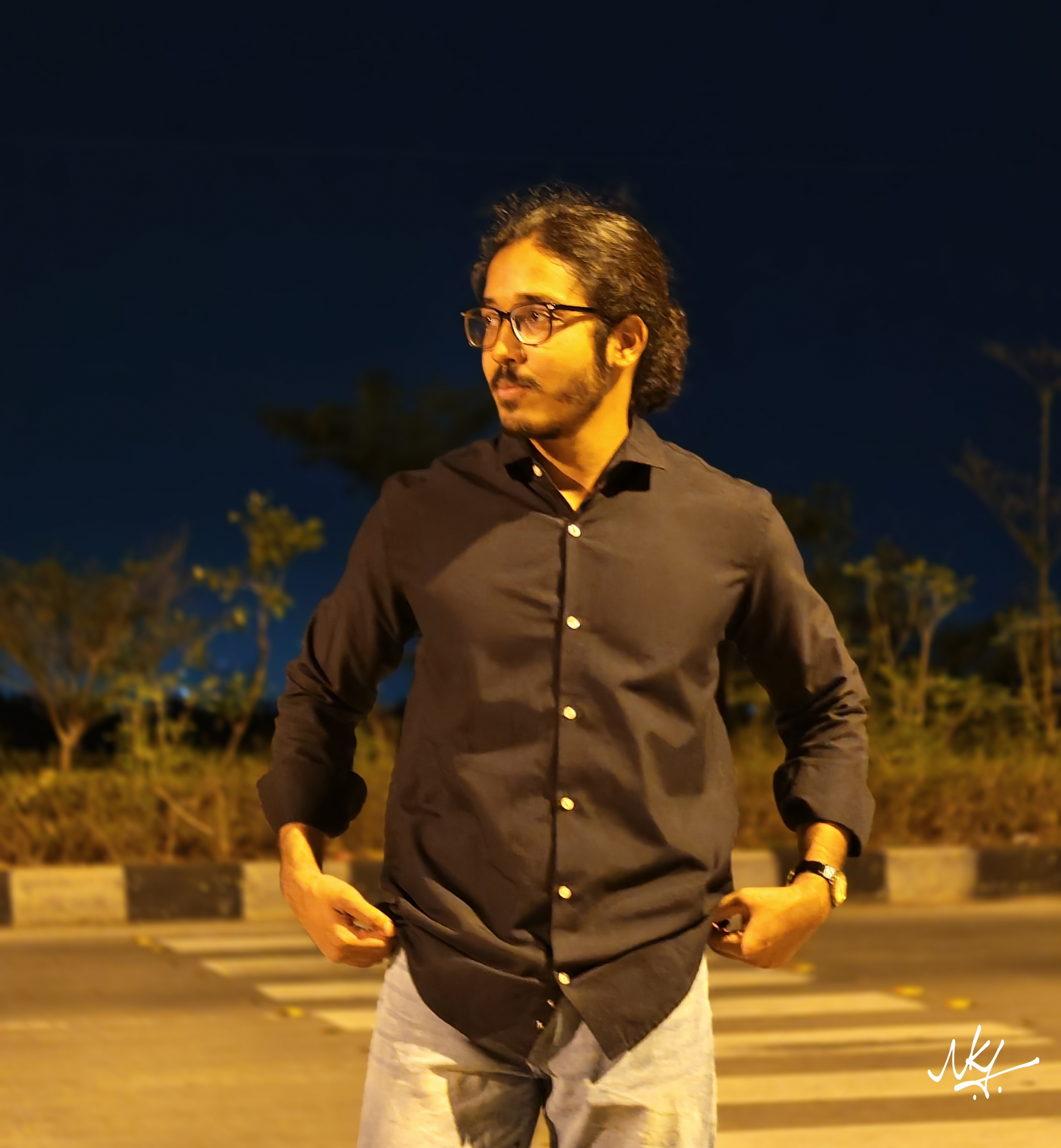 Umair Hazrami standing outdoors at night, wearing a dark shirt.