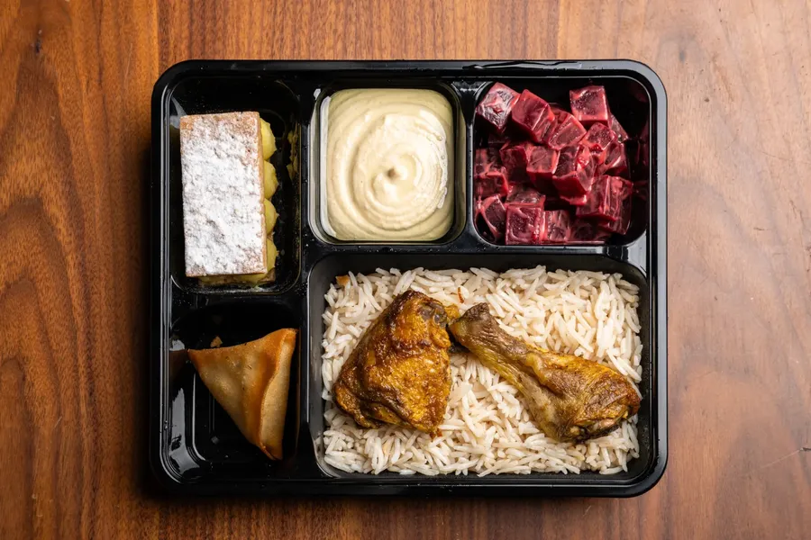 A prepared catering meal with rice, chicken, pastry and sides.