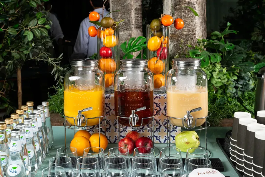 Avala Catering drinks station with fruit-filled dispensers and bottled water.