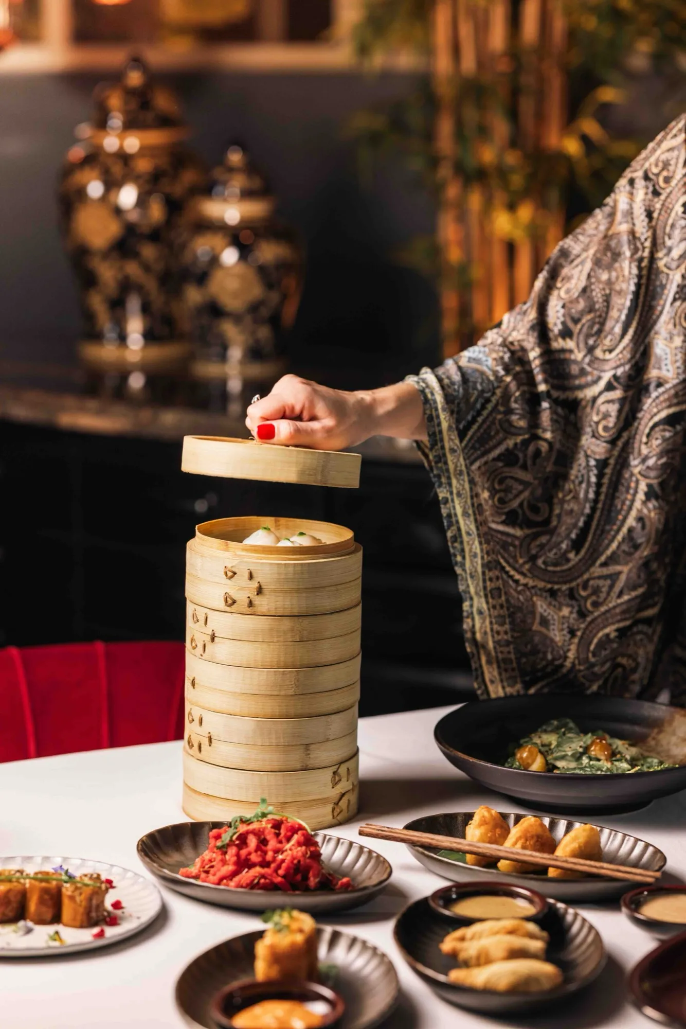 Dim sum steamer lifted by a guest at the table.