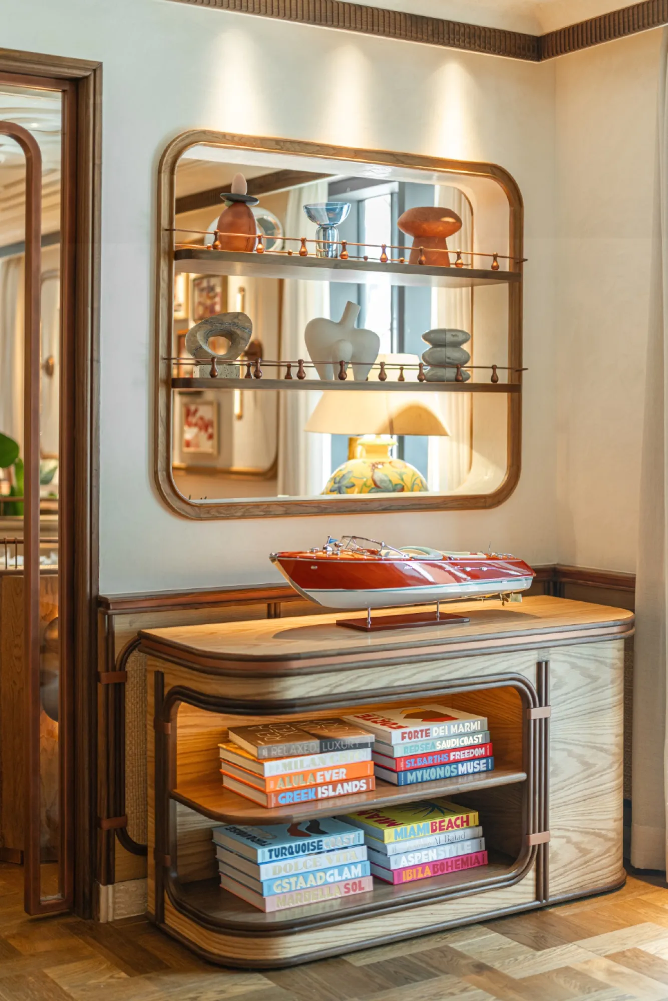 Mirror, lamp and model boat on a sideboard.