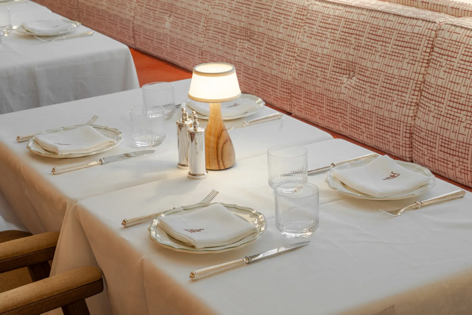 Table laid with white linen and a small lamp.