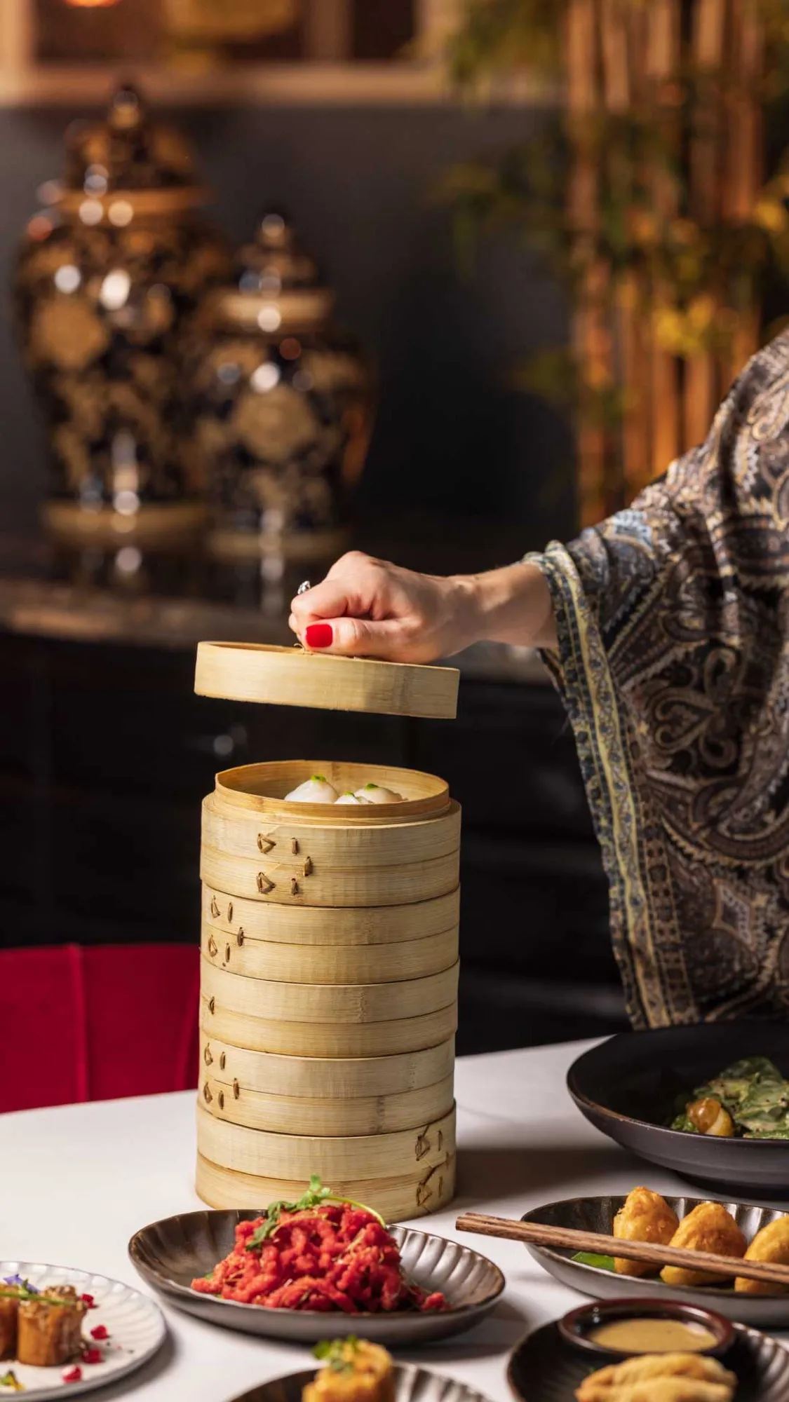Bamboo dim sum steamers lifted at the table.