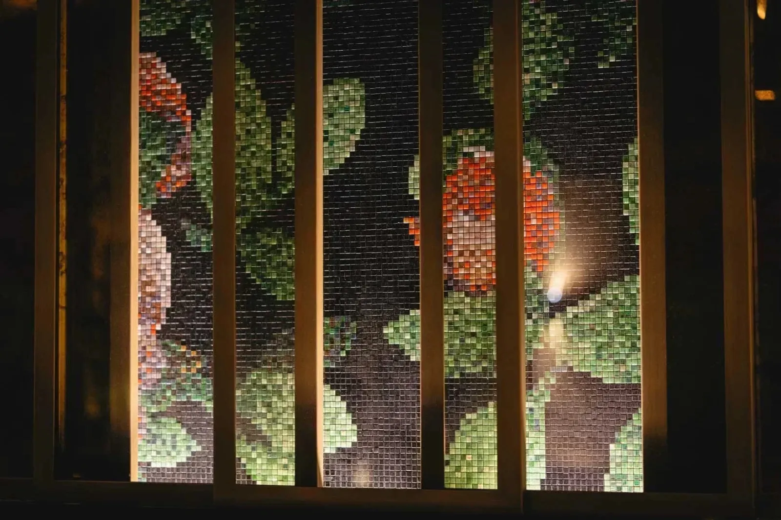 Mosaic art wall behind wooden screens.